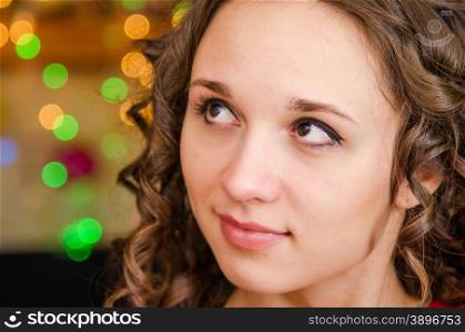 Close-up portrait of a young European girl against a blurred background of Christmas lights. Portrait a young girl on the background of Christmas lights