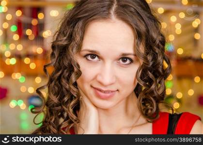 Close-up portrait of a young European girl against a blurred background of Christmas lights. Portrait a girl on background of blurred lights