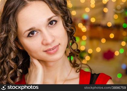 Close-up portrait of a young European girl against a blurred background of Christmas lights. Portrait girl on a background of blurred Christmas lights