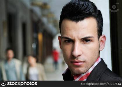 Close-up portrait of a young handsome man, model of fashion, wearing jacket and shirt in urban background