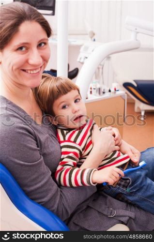 Close-up portrait of a young smiling mother and her son on reception at the dentist. Mom and her little son visiting the dentist