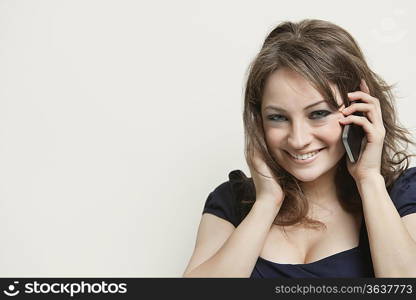 Close-up portrait of a young woman on call over gray background