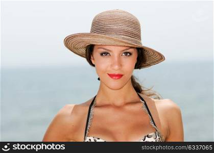 Close up portrait of an beautiful woman smiling with a sun hat on a tropical beach
