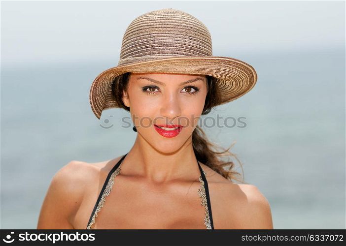 Close up portrait of an beautiful woman smiling with a sun hat on a tropical beach
