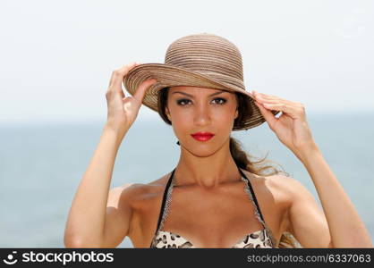 Close up portrait of an beautiful woman with a sun hat on a tropical beach