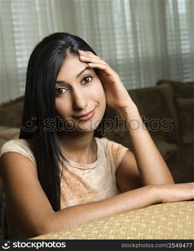 Close up portrait of Asian/Indian young woman sitting on couch.