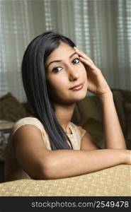 Close up portrait of Asian/Indian young woman sitting on couch.