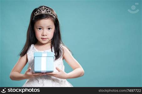 Close up portrait of asian little happy girl with blue present box , isolated on light blue background .