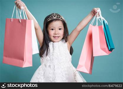 Close up portrait of asian little happy girl with shopping bags , isolated on light blue background .