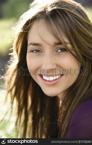 Close-up portrait of attractive young Caucasian woman with long brown hair smiling at viewer.