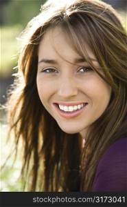 Close-up portrait of attractive young Caucasian woman with long brown hair smiling at viewer.
