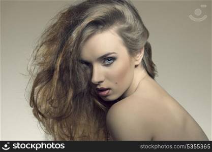 close-up portrait of attractive young female posing with provocative expression with naked shoulders and wild bushy hair
