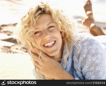 Close up portrait of attractive young woman lying in sand on Maui, Hawaii beach smiling.