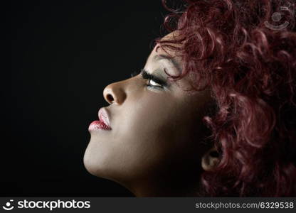 Close up portrait of beautiful black woman on black background with red hair. Afro hairstyle. Studio shot