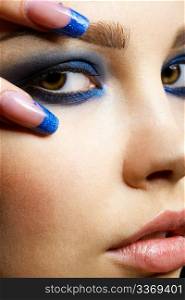 Close-up portrait of beautiful brunette with blue eye shadow make up and manicure