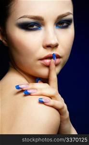 close-up portrait of beautiful brunette with blue eye shadow make up and manicure
