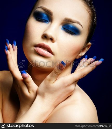 close-up portrait of beautiful brunette with blue eye shadow make up and manicure
