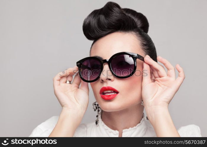 Close Up portrait of beautiful vintage styling model wearing round black sunglasses. Updo, large earrings