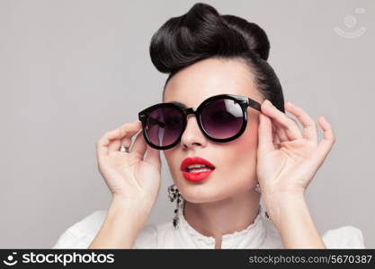 Close Up portrait of beautiful vintage styling model wearing round black sunglasses. Updo, large earrings