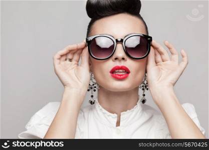 Close Up portrait of beautiful vintage styling model wearing round black sunglasses. Updo, large earrings