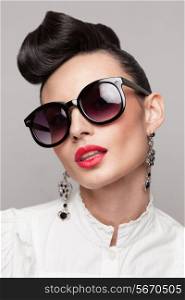 Close Up portrait of beautiful vintage styling model wearing round black sunglasses. Updo, large earrings