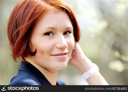 Close-up portrait of beautiful woman with red hair posing outdoors