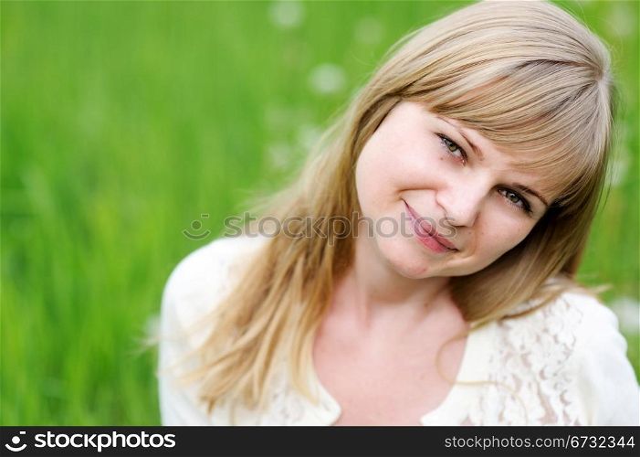 Close-up portrait of beautiful young blond woman in white blouse posing outdoors
