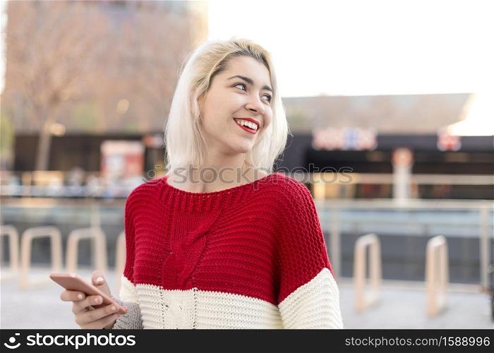 Close up portrait of beautiful young girl using cellphone outdoors in the city