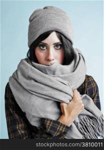 Close up portrait of beautiful young woman wearing a scarf and a woolly hat - studio shot