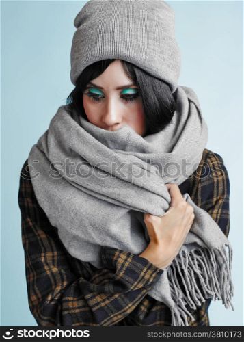 Close up portrait of beautiful young woman wearing a scarf and a woolly hat - studio shot