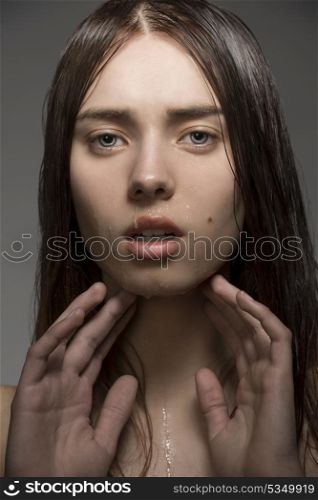 close-up portrait of beauty clean girl with natural style, wet visage skin and hair. Looking in camera with hands near the face