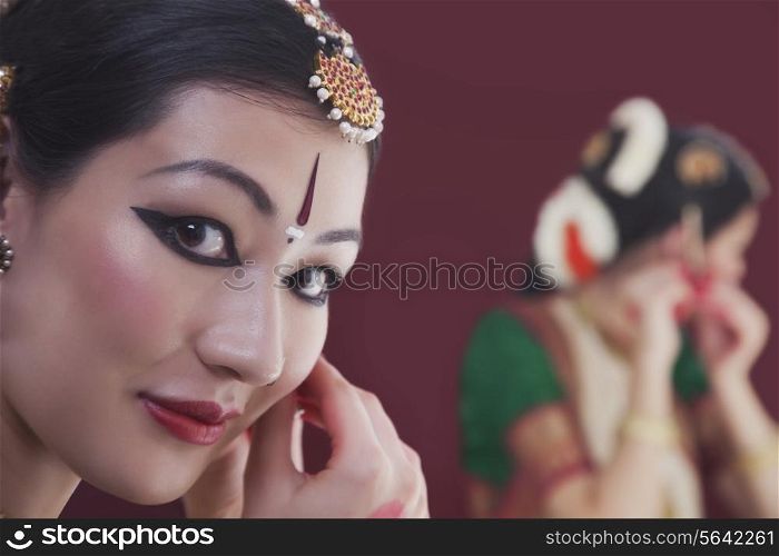 Close-up portrait of Bharatanatyam dancer getting dressed in front of mirror