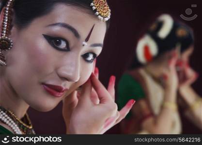Close-up portrait of Bharatanatyam dancer getting dressed on black background