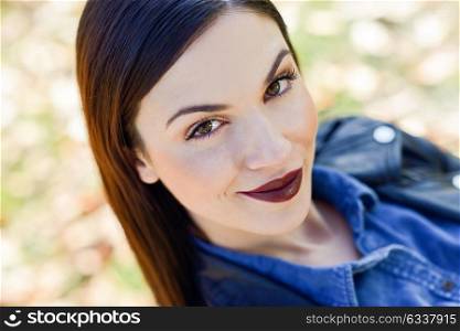 Close-up portrait of brunette young woman, model of fashion, in urban background. Girl with beautiful lips maked-up in red