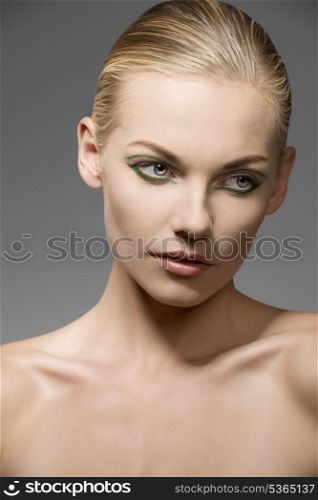 close-up portrait of caucasian female with blonde hair and beauty skin posing with pretty green make-up and naked shoulders
