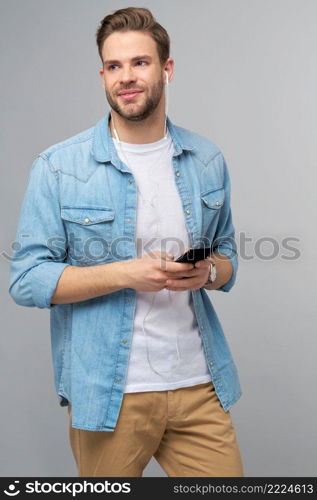 Close up portrait of cheerful young man enjoying listening to music wearing casual jeans outfit.. Close up portrait of cheerful young man enjoying listening to music wearing casual jeans outfit