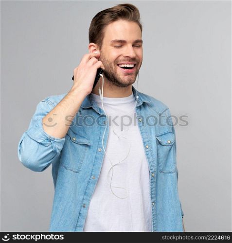 Close up portrait of cheerful young man enjoying listening to music wearing casual jeans outfit.. Close up portrait of cheerful young man enjoying listening to music wearing casual jeans outfit