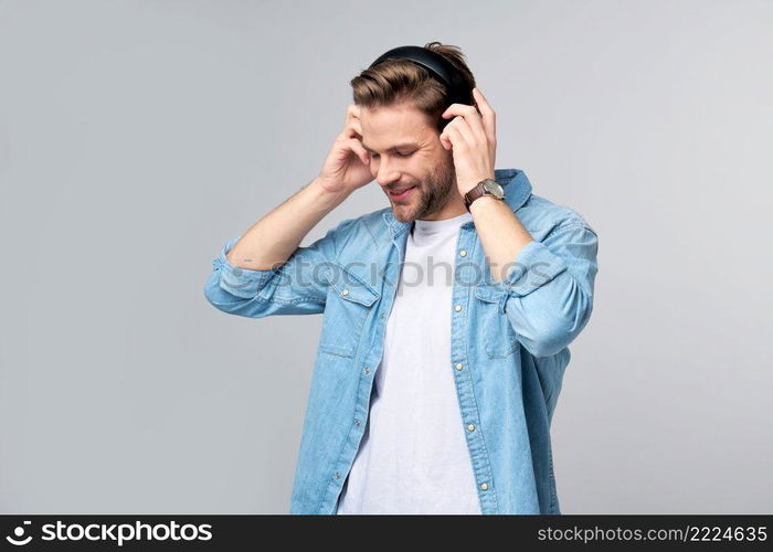 Close up portrait of cheerful young man enjoying listening to music wearing casual jeans outfit.. Close up portrait of cheerful young man enjoying listening to music wearing casual jeans outfit