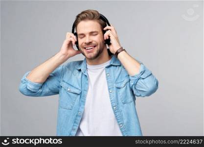 Close up portrait of cheerful young man enjoying listening to music wearing casual jeans outfit.. Close up portrait of cheerful young man enjoying listening to music wearing casual jeans outfit