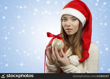 close-up portrait of christmas girl with winter clothes taking bauble in the hands, wearing red santa claus hat