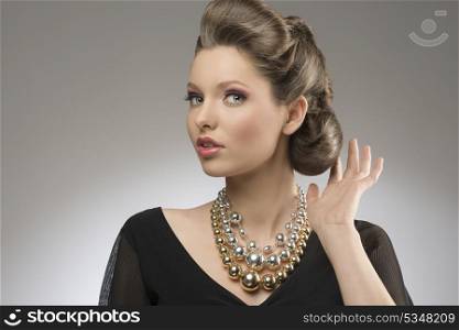 close-up portrait of fashion pretty girl with brown elegant hair-style and bright big necklace.