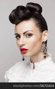 Close Up portrait of fashionable brunette model. Updo, vintage accessories. Makeup and hairstyle. Red lips, large earrings