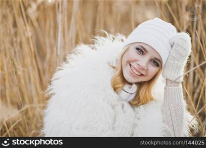 Close-up portrait of girl in white furry jacket and hat in the winter among the reeds.. Beautiful blond stands in winter in the reedbeds 9149.