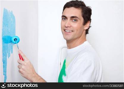 Close-up portrait of happy man painting wall with roller