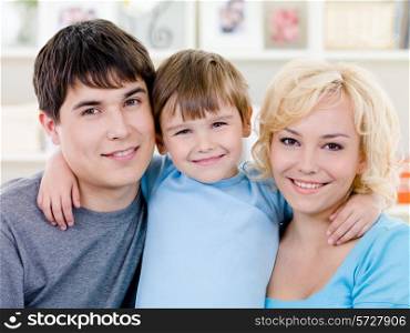 Close-up portrait of happy smiling family with little son - indoors