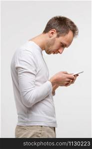 Close up portrait of man looking and using smart phone with scoliosis, side view, isolated on gray background. Rachiocampsis, kyphosis curvature of neck, Incorrect posture, orthopedics concept