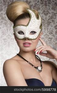 close-up portrait of masquerade pretty blonde girl with elegant hair-style and necklace and cute decorated white mask. Looking in camera