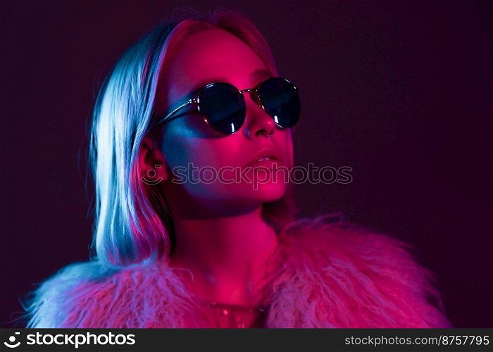 Close up portrait of millennial pretty glamour girl in fluffy fur coat in neon light. Dyed blue and pink hair. Mysterious hipster teenager in glasses. Close up portrait of millennial pretty glamour girl in fluffy fur coat in neon light. Dyed blue and pink hair. Mysterious hipster teenager in glasses.