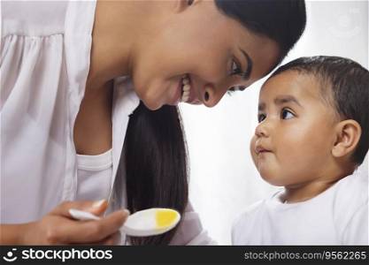 Close-up portrait of mother feeding her little baby with spoon