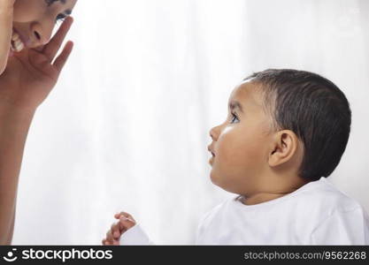 Close-up portrait of mother playing hide and seek with baby while feeding